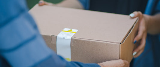 A package of mail being passed from one person's hands to another's.