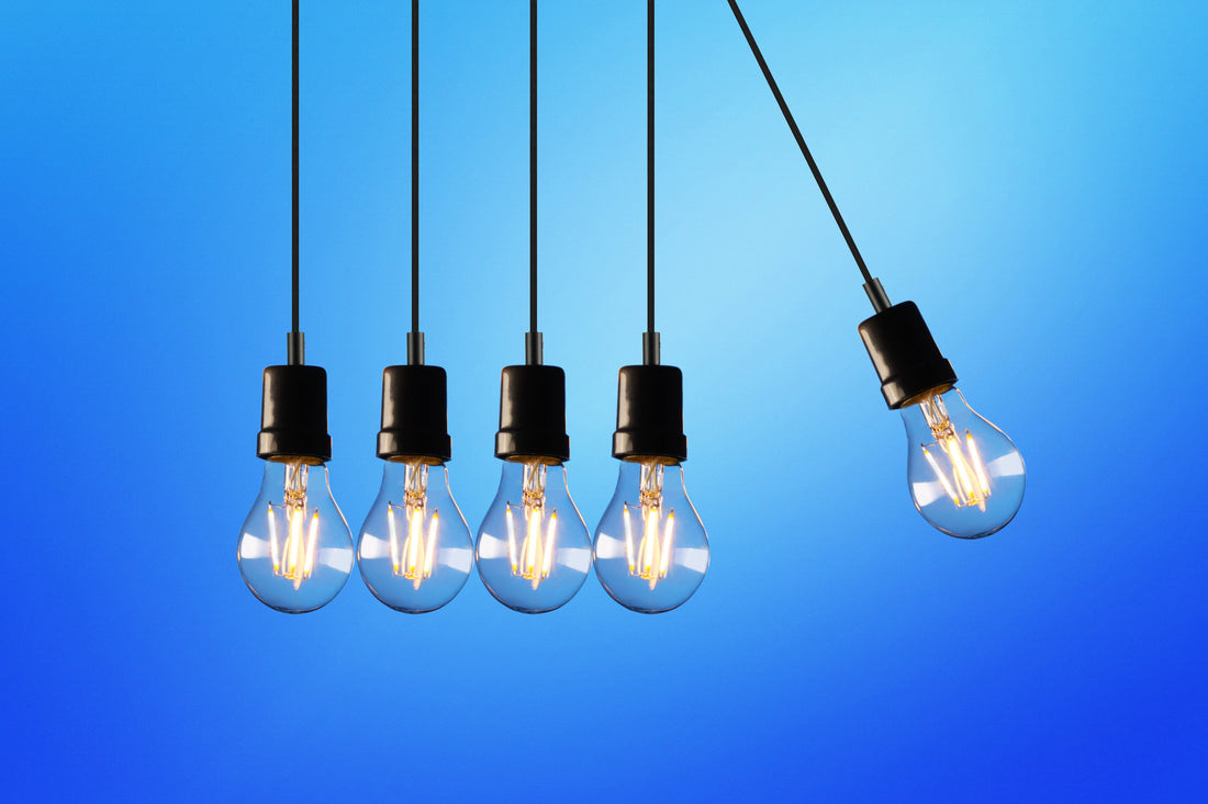Light bulbs suspended from ceiling in front of blue wall.