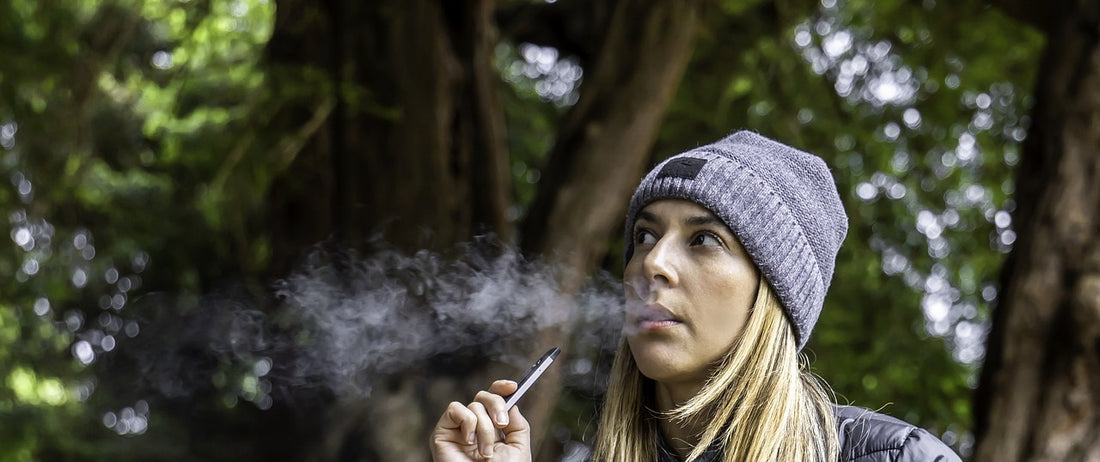 Person vaping a portable dry herb vape in a forest.