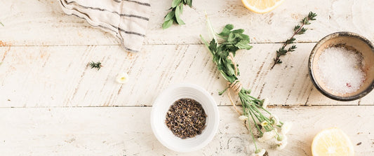 An array of fresh herbs on a table: lavender, cloves and lemon.