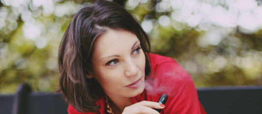 A person vaping a portable dry herb vaporizer outside.