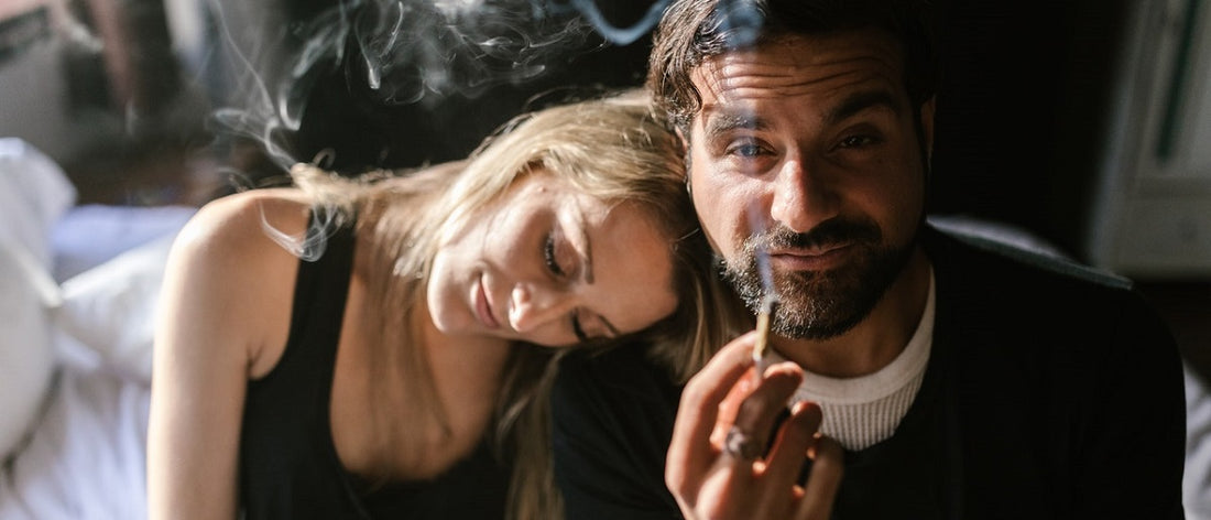 Two people smoking a joint on a bed.