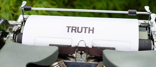 A typewriter with a sheet of paper saying "TRUTH" on it.