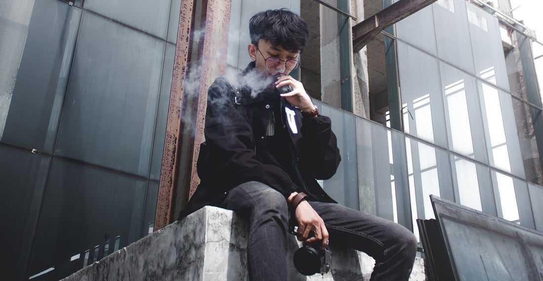 Person sitting in a construction site holding a camera and vaping.